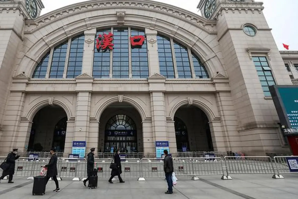 Orang-orang berjalan melewati Stasiun Kereta Api Hankou yang ditutup di Wuhan, Provinsi Hubei, China, Kamis (23/1/2020). Pemerintah China mengisolasi Kota Wuhan yang berpenduduk sekitar 11 juta jiwa untuk menahan penyebaran virus corona.