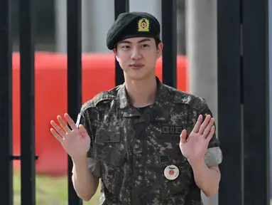 Kim Seok Jin, yang dikenal dengan nama panggung Jin BTS melambai setelah keluar dari dinas wajib militernya di luar pangkalan militer di Yeoncheon, Rabu (12/6/2024). (Jung Yeon-je / AFP)