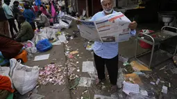 Seorang pria membaca koran di pasar grosir di Bengaluru, India, Rabu (13/4/2022). Orang-orang telah kembali beraktivitas normal setelah pihak berwenang mencabut pembatasan COVID-19 termasuk mengenakan masker wajah di tempat-tempat umum. (AP Photo/Aijaz Rahi)