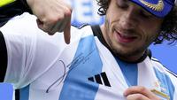 Pebalap Tim Mooney VR46, Marco Bezzecchi menunjukkan jersey Timnas Argentina bertandatangan Lionel Messi saat menjuarai MotoGP Argentina 2023 di Autódromo Termas de Río Hondo, Argentina, Senin (03/04/2023) dini hari WIB. Selebrasi tersebut diketahui meniru sang gurunya, Valentino Rossi yang dilakukan pada musim 2015 silam. (AP Photo/Natacha Pisarenko)
