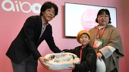 Kepala Kelompok Usaha Robotika AI, Izumi Kawanishi (kiri) menyerahkan sebuah tempat yang berisi robot anjing dari Sony, Aibo kepada pemilik baru yang telah membeli pada acara peresmian di Tokyo, Jepang (11/1). (AFP Photo/Kazuhiro Nogi)