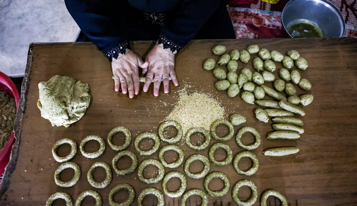 Kesibukan anggota keluarga Palestina menyiapkan kue-kue tradisional untuk dijual sebagai persiapan liburan Idul Fitri mendatang, di kota Rafah, Jalur Gaza, Selasa (4/5/2021). Pembuatan kue tradisional untuk Hari Raya Idul Fitri atau Lebaran yang menandai akhir bulan Ramadhan. (KATA KHATIB/AFP)
