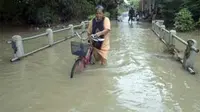 Warga melintasi jembatan yang terendam luapan Bengawan Solo di Sukoharjo, Jateng. Luapan air Bengawan Solo mengakibatkan ribuan rumah terendam. (Antara)