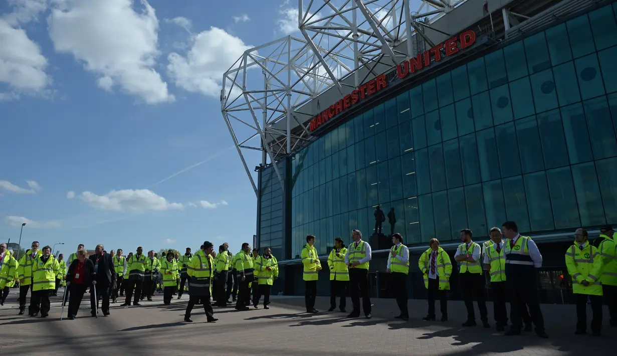Petugas keamanan berjaga di luar Stadion Old Trafford, usai penemuan benda mencurigakan di salah satu tribun, Inggris, Minggu (15/5). Penemuan benda mencurigakan itu membuat Laga terakhir Liga Inggris antara MU Vs Bournemouth ditunda. (Oli SCARFF/AFP)