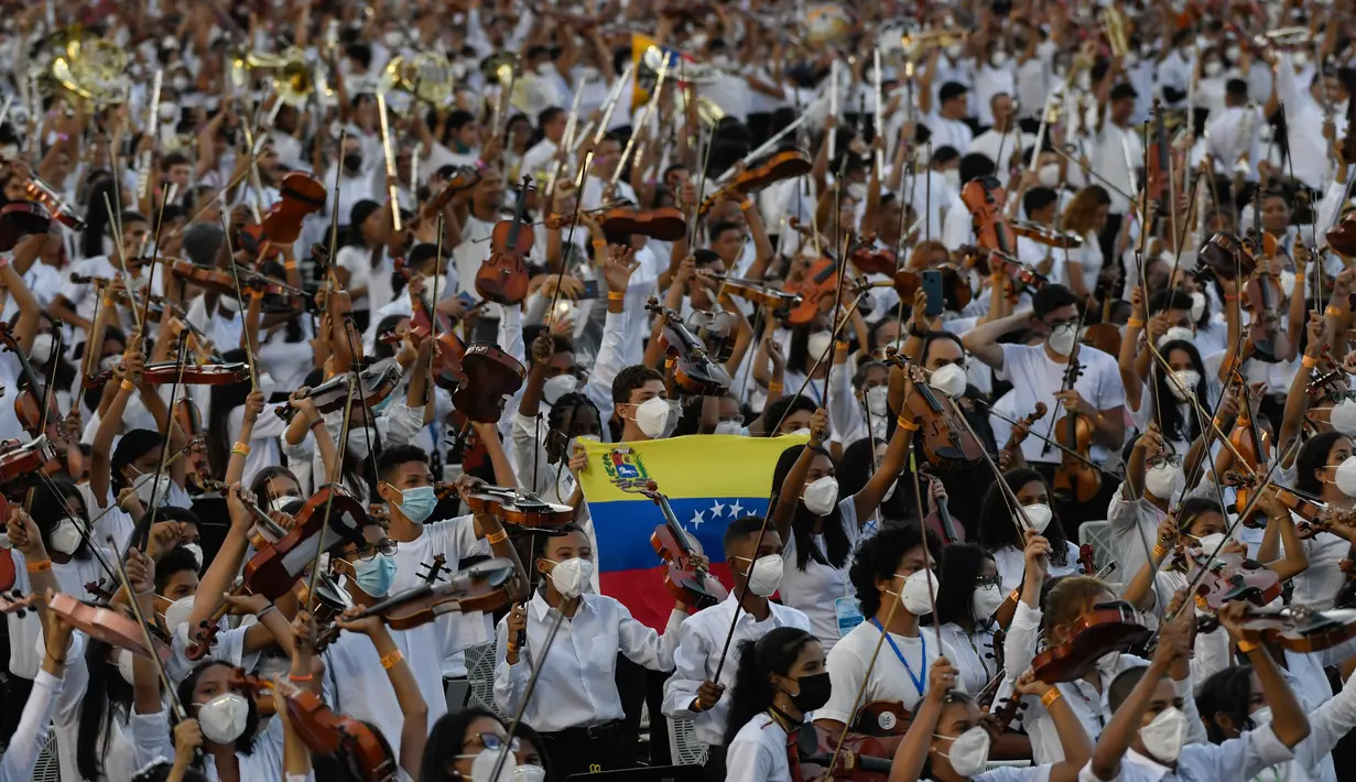 Musisi dari National System of Orchestras of Venezuela berusaha memecahkan rekor dunia bermain orkestra terbesar di dunia, di Caracas pada 13 November 2021. Para musisi berusia antara 12 dan 77 tahun itu kompak mengenakan celana hitam, kemeja putih, dan masker. (Federico PARRA/AFP)