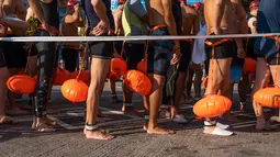 Perenang menunggu di garis start saat lomba renang tahunan melintasi Pelabuhan Victoria Hong Kong, Minggu (12/12/2021). Lomba renang tahunan itu diadakan untuk pertama kalinya dalam tiga tahun, setelah dibatalkan karena aksi demonstrasi besar-besaran dan kemudian pandemi COVID-19. (Bertha WANG/AFP)