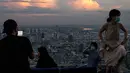 Orang-orang memandangi cakrawala Bangkok dari dek observasi di gedung pencakar langit King Power Mahanakhon saat matahari terbenam pada 25 Oktober 2021. Gedung tertinggi di Thailand itu juga membuka rooftop bar dan lokasi lantai tembus pandang seluar 63 meter persegi. (Jack TAYLOR / AFP)