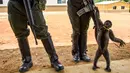 Seekor monyet berusaha menarik senjata polisi wanita di Agua Bonita, Kolombia (25/10). Tingkah Monyet ini asyik bermain dengan senjata laras panjang milik polwan tersebut. (AFP Photo/Raul Arboleda)