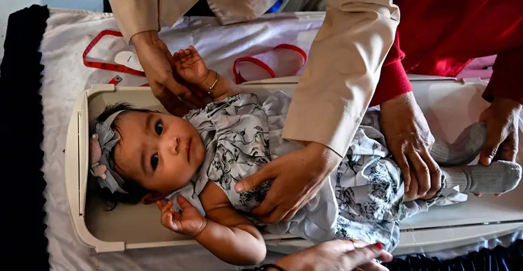 Seorang petugas kesehatan menimbang berat bayi dalam program pemeriksaan kesehatan bulanan untuk anak-anak di sebuah pusat layanan terpadu di Banda Aceh, Senin,  10 Agustus 2026. (AFP/ Chaideer Mahyuddin)