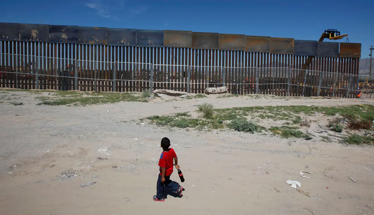 Seorang anak melihat pekerja dari Amerika Serikat saat membangun dinding perbatasan AS-Meksiko di Sunland Park, AS (09/9). Amerika Serikat dan Mexico merupakan dua negara yang memiliki batas geografis yang berdekatan. (REUTERS/Jose Luis Gonzalez)