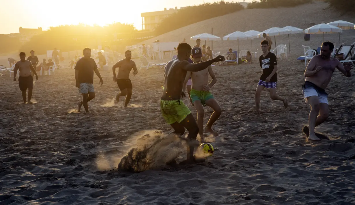 Para pria bermain sepak bola di pantai di tengah gelombang panas musim panas di Carilo, provinsi Buenos Aires, Argentina (14/1/2022). Argentina menghadapi gelombang panas paling ekstrem dalam sejarah dengan suhu yang melonjak di atas 40 derajat celcius. (AP Photo/Rodrigo Abd)