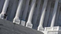 Penjaga keamanan berdiri di tangga Gedung Capitol AS di Capitol Hill, Washington, DC. Rabu (3/3/2021).  Kepolisian meningkatkan keamanan di wilayah Washington DC, setelah intelijen menemukan dugaan plot terbaru untuk 'menembus Capitol' pada Kamis (4/3) waktu setempat. (Eric BARADAT/AFP)