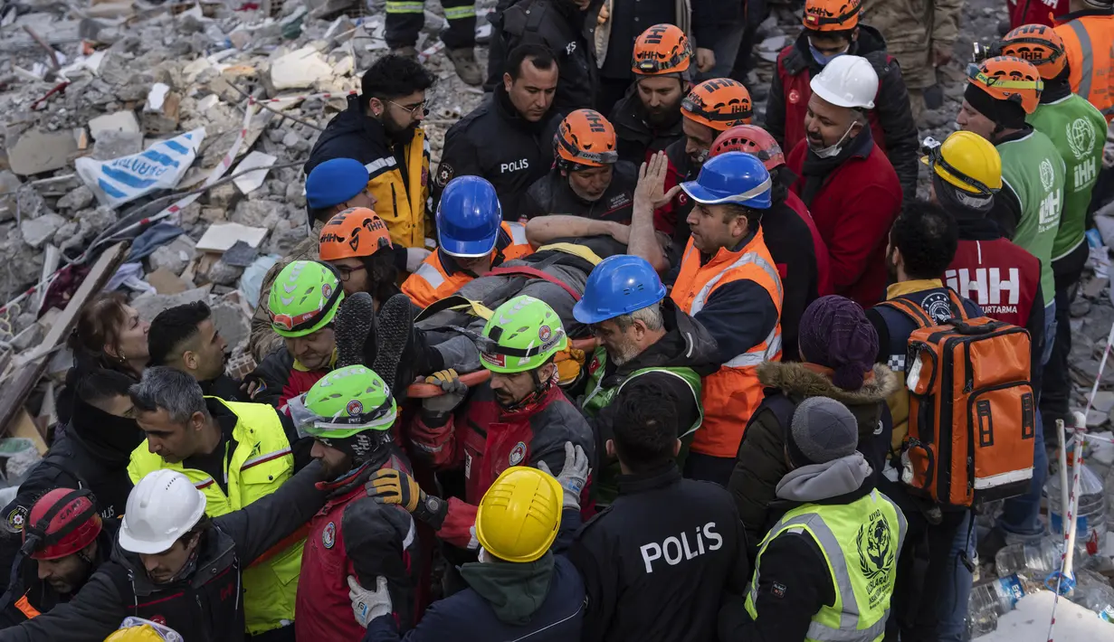 Haci Murat Kilinc dibawa melewati kerumunan dengan tandu setelah dia diselamatkan di bawah bangunan yang hancur di Iskenderun, Turki tenggara, Jumat (10/2/2023). Pasangan suami istri ditarik dari bawah puing-puing bangunan yang runtuh di Iskenderun setelah menghabiskan 109 jam terkubur di dalam celah kecil. (AP Photo/Petros Giannakouris)