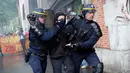 Polisi anti huru-hara mengamankan seorang demonstran saat terjadi bentrokan di Paris, Prancis (23/5). Mereka memprotes kebijakan pemerintah terkait pemangkasan 120.000 pekerjaan pada 2022. (AP/Christophe Ena)