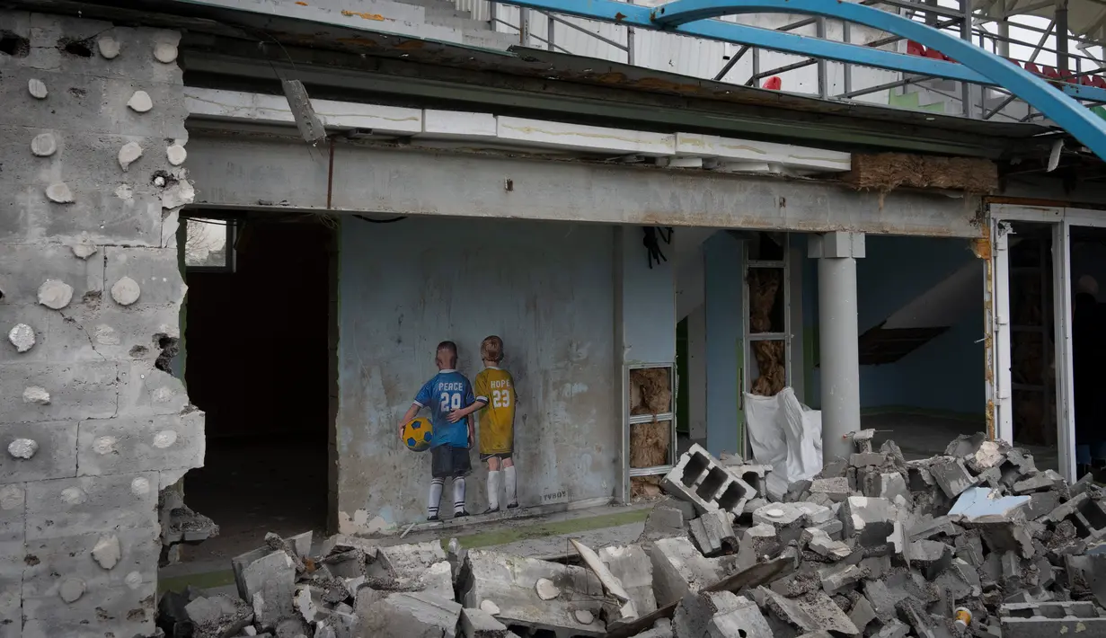 Sebuah karya seni dari seniman jalanan terkenal TvBoy dibuat pada dinding stadion pusat yang rusak akibat serangan Rusia terhadap Ukraina di Kota Irpin, Ukraina, 30 Januari 2023. Karya seni yang dibuat untuk menghormati para korban perang Rusia-Ukraina tersebut mengandung pesan kelahiran kembali dan harapan serta berharap agar konflik segera berakhir. (AP Photo/Efrem Lukatsky)