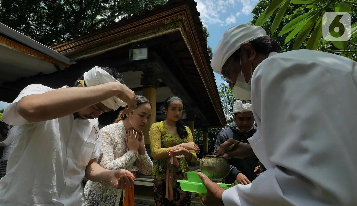 Umat Hindu diberikan air suci selama Upacara Tawur Agung Kesanga di Pura Aditya Jaya, Pulo Gadung, Jakarta Timur, Rabu (1/3/2022). Upacara ini bermakna sebagai wujud keselarasan antara umat manusia dengan alam.  (Liputan6.com/Herman Zakharia)