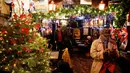 Seorang pelanggan menikmati dekorasi natal di bar The Churchill Arms di London, Inggris, 20 Desember 2016. Menyambut Natal, bagian luar bangunan bar tersebut ditutupi lebih dari 80 pohon natal dan hampir 22.000 lampu berkelap-kelip. (REUTERS/Neil Hall)
