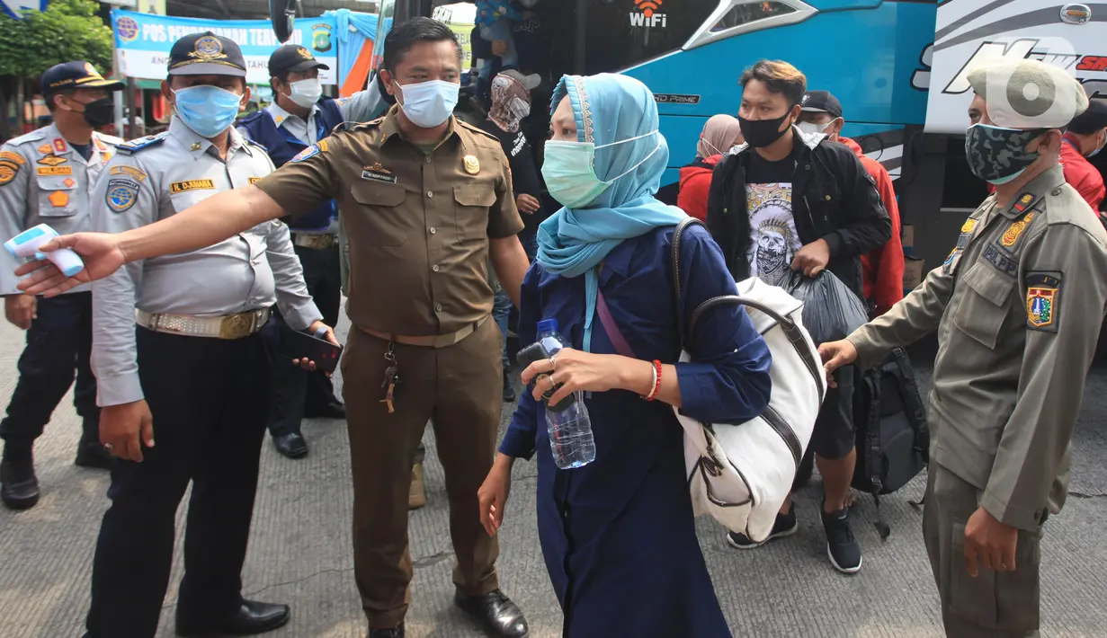 Petugas mengarahkan penumpang yang turun dari bus Antar Kota Antar Provinsi (AKAP) di Terminal bus Kalideres, Jakarta Barat, Senin (17/5/2021). Arus balik pemudik mulai terlihat di sejumlah terminal di Jakarta, salah satunya di Terminal Kalideres. (Liputan6.com/Angga Yuniar)