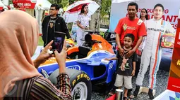 Pengunjung berfoto bersama di replika mobil Formula 1 yang ditunggangi pembalap Indonesia, Rio Haryanto pada acara Nonton Bareng F1 GP Australia 2016 Pertamina di Mall Bintaro Xchange, Tangerang Selatan, Minggu (20/3). (Liputan6.com/Fery Pradolo)