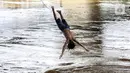 Seorang anak melompat ke Sungai Ciliwung saat banjir melanda Jalan Bina Warga Rt 005/Rw 07 Kelurahan Rawa Jati, Jakarta, Senin (8/2/2021). Banjir setinggi 60-190 cm tersebut disebabkan oleh luapan air Sungai Ciliwung dan curah hujan Jakarta yang tinggi. (Liputan6.com/Johan Tallo)