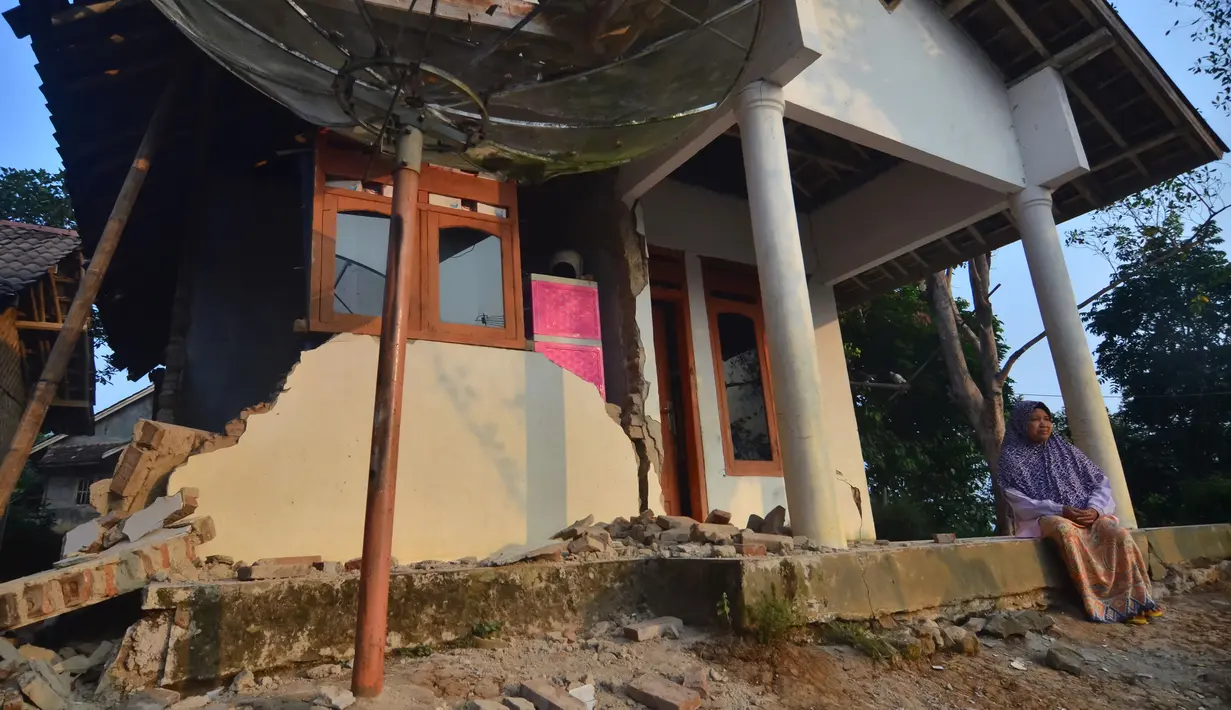 Warga duduk di rumah yang rusak usai gempa melanda Pandeglang, Banten, Sabtu (3/8/2019). Gempa Banten berpusat di kedalaman 48 kilometer Barat Daya Pandeglang. (RONALD SIAGIAN/AFP)