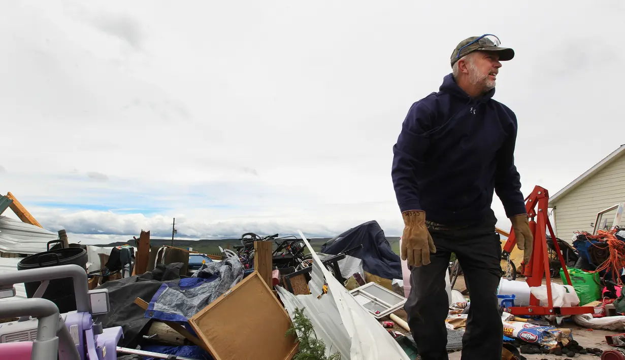 Seorang pria membantu membersihkan puing-puing sisa rumah yang dihantam tornado di Laramie County, Wyoming, AS (29/5). (Jacob Byk/The Wyoming Tribune Eagle via AP)