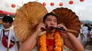 Seorang pemuja dari Kuil Samkong menusukkan dua payung pada pipinya ketika beratraksi dalam Festival Vegetarian di Phuket, Thailand, Selasa (4/10). (REUTERS/Jorge Silva)