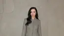 Mikey Madison tampil dengan gaya office look mengenakan set abu-abu dari atasan blazer dipadukan mini skirt. Sambil membawa clucth hitam serasi dengan heelsnya. [Dok. DIOR]