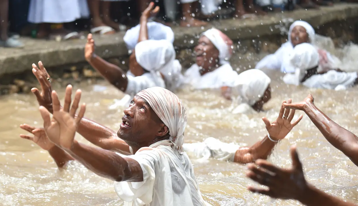 Pengikut Voodoo Haiti mandi di kolam suci selama upacara voodoo di Souvenance, Haiti (4/1). Sejumlah ritual digelar para pengikuti Voodoo Haiti ini selam akhir pekan perayaan Paskah. (AFP/Hector Retamal)