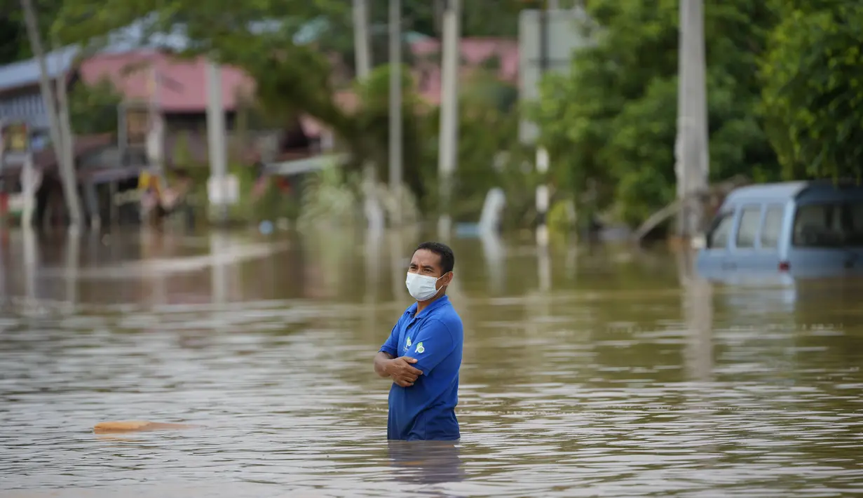 Seorang pria mengarungi jalan yang banjir di Hulu Langat, di luar Kuala Lumpur, Malaysia, Minggu (19/12/2021). Kuala Lumpur dan perkampungan sekitarnya dilanda banjir akibat hujan deras selama dua hari, menyebabkan ribuan warga mengungsi dan banyak jalan yang memutus akses. (AP Photo/Vincent Thian)
