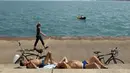 Chet Ski (kiri) dan Richard Paul berjemur di Danau Michigan di Montrose Beach, Chicago, Selasa (27/4/2021). Warga AS yang telah menerima vaksin COVID-19 tidak lagi diwajibkan mengenakan masker saat berada di luar ruangan kecuali berada di tengah kerumuman orang asing. (AP Photo/Shafkat Anowar)