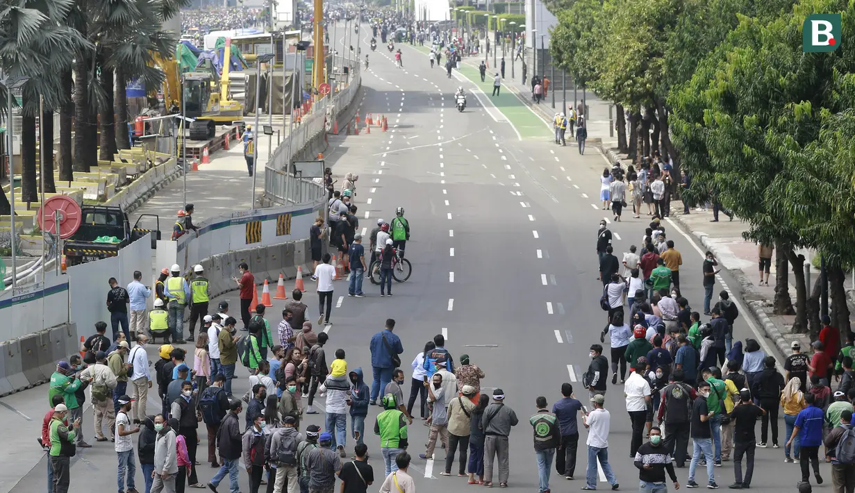 Warga tumpah ruah hingga ke jalan saat melihat parade pembalap MotoGP di depan Sarinah Thamrin, Jakarta Pusat. Sebanyak  20 pembalap melakukan parade motor dari Istana Merdeka menuju Hotel Kempinski di Bundaran HI Jakarta Pusat, Rabu (16/03/2022). (Bola.com/M Iqbal Ichsan)