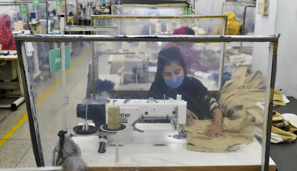 Para buruh bekerja pada stasiun mereka yang dipisahkan oleh sekat sebagai tindakan pencegahan terhadap penularan virus corona COVID-19 di pabrik garmen Civil Engineers Limited, Dhaka, Bangladesh, 17 Agustus 2021. (Munir UZZAMAN/AFP)