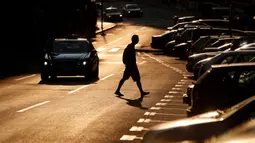 Seorang pria melintasi jalan saat matahari terbenam di Beograd, Serbia, Kamis (2/7/2020). (AP Photo/Darko Vojinovic)