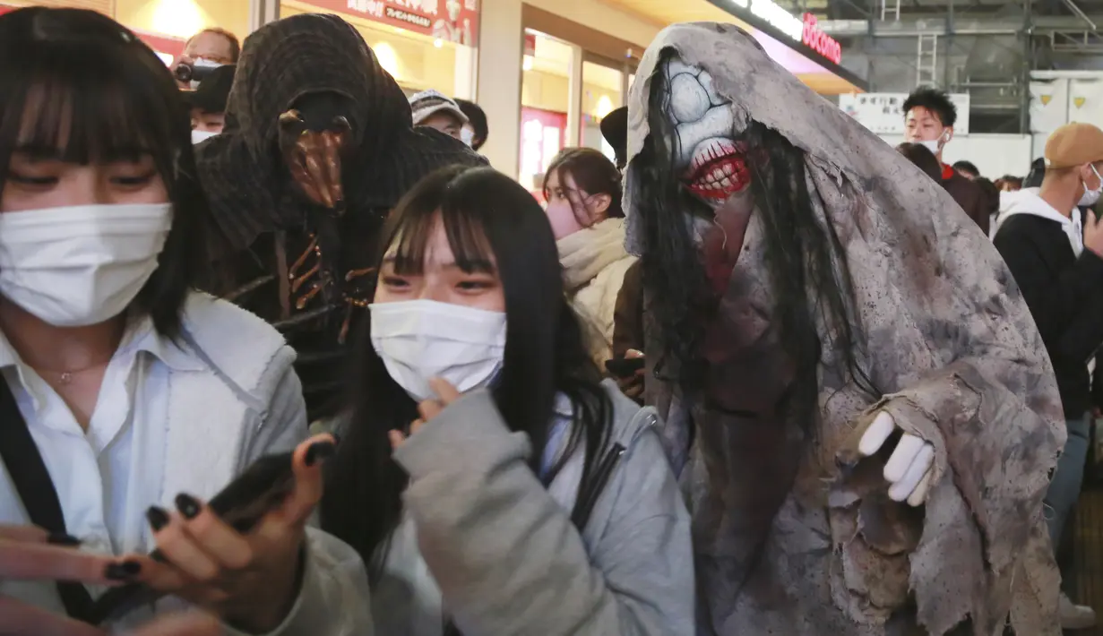 Orang-orang yang mengenakan kostum Halloween berjalan melalui distrik Shibuya yang populer di Tokyo, Minggu (31/10/2021). Daerah di sekitar Stasiun Shibuya dipadati anak-anak muda yang berdandan selama Halloween setiap tahun. (AP Photo/Koji Sasahara)