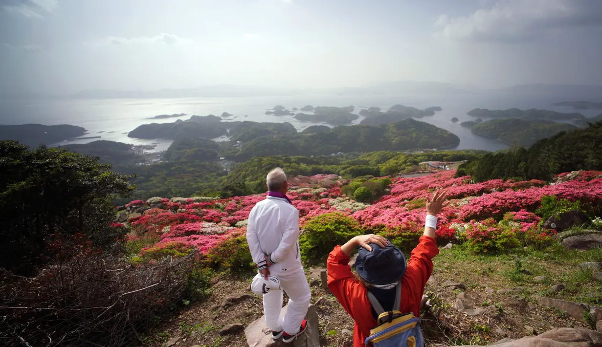 Wisatawan mengamati bunga-bunga Azalea berwarna-warni yang mekar di taman Nagushiyama, Prefektur Nagasaki, barat daya Jepang, 15 April 2018. Keindahan dari bunga cantik ini hanya bisa disaksikan pada April hingga Mei saja. (AP Photo/Eugene Hoshiko)