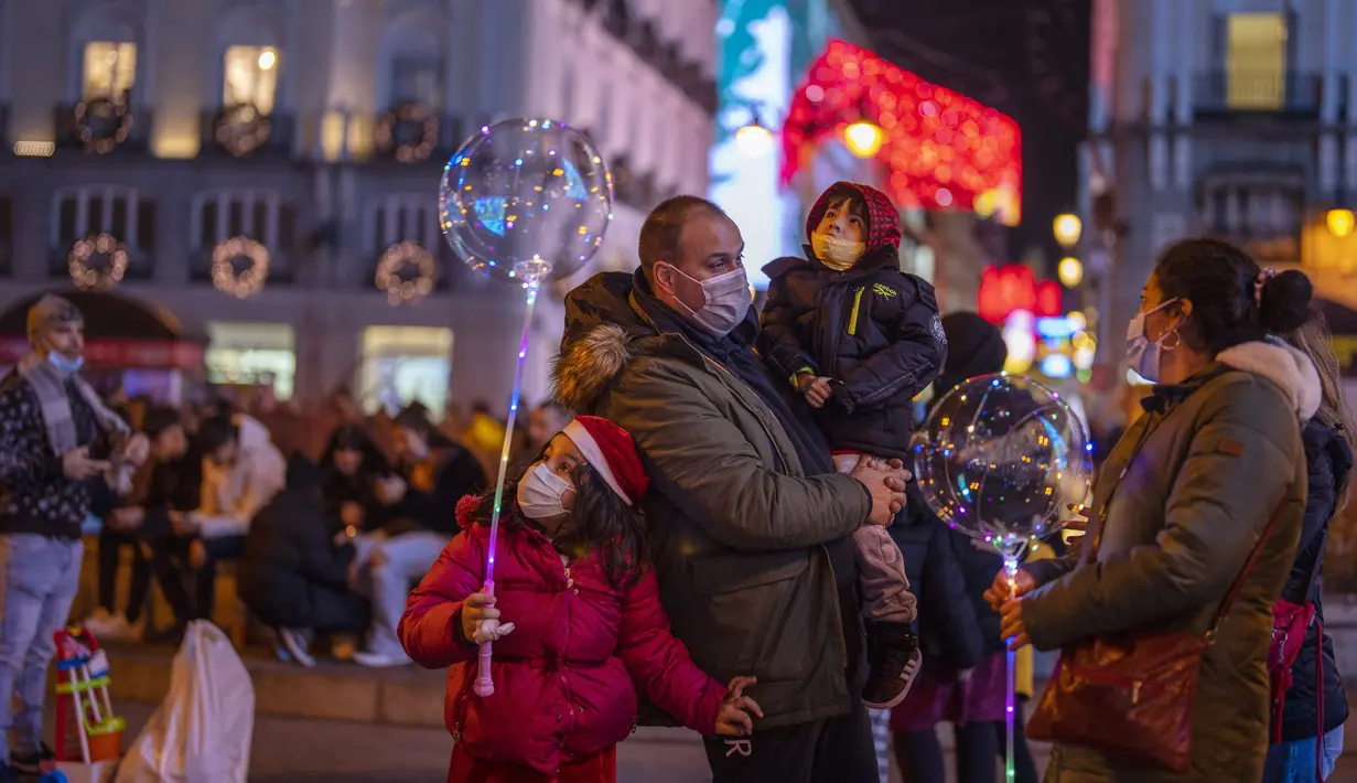 Orang-orang yang memakai masker menikmati lampu Natal di pusat kota Madrid, Rabu (22/12/2021). PM Spanyol Pedro Sanchez mengadakan rapat Kabinet khusus untuk mengesahkan undang-undang yang mewajibkan penggunaan masker di luar ruangan di tengah lonjakan rekor kasus COVID-19. (AP Photo/Manu Fernandez)
