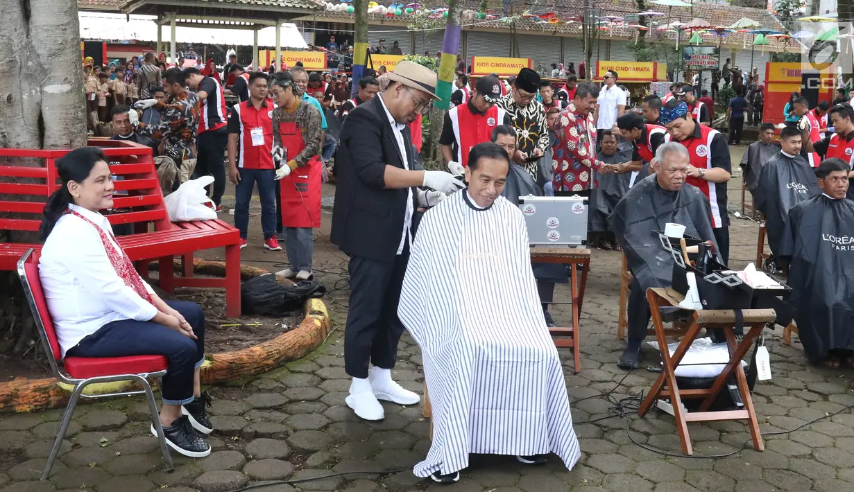 Presiden Joko Widodo disaksikan Ibu Negara Iriana saat mengikuti acara cukur rambut massal di Garut, Jawa Barat, Sabtu (19/1). Dalam acara cukur rambut massal ini, rambut Jokowi dicukur oleh tukang cukur langganannya, Herman. (Liputan6.com/Angga Yuniar)