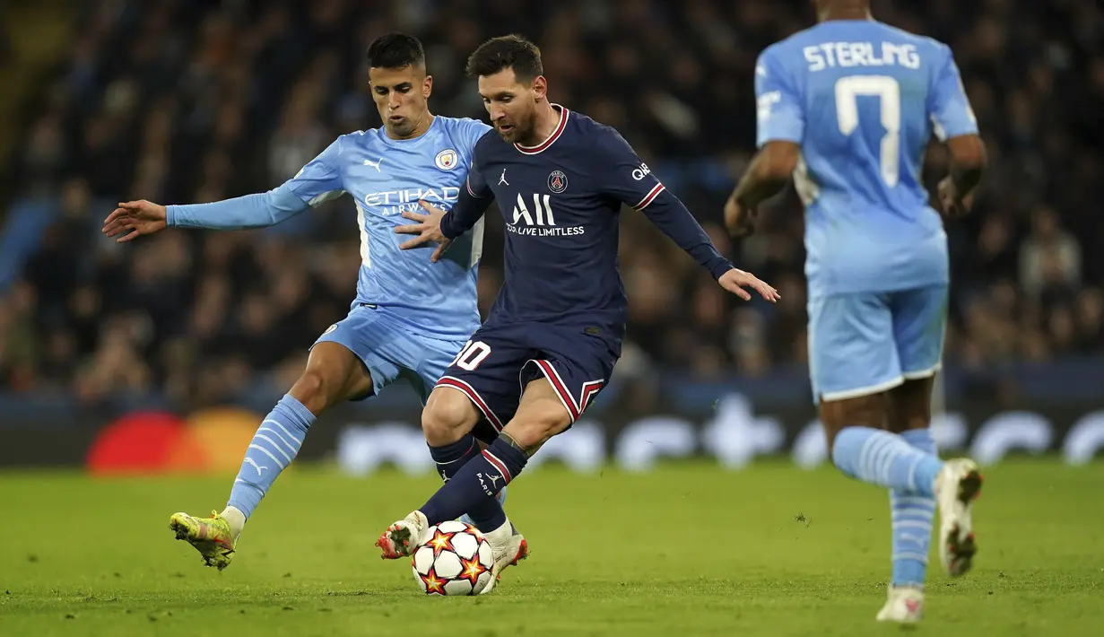 Bek Manchester City Joao Cancelo berebut bola dengan penyerang Paris Saint Germain (PSG) Lionel Messi pada match day ke-5 fase grup Liga Champions di Etihad Stadium, Kamis (25/11/2021) dinihari WIB. Manchester City menang comeback melawan PSG 2-1. (Tim Goode/PA via AP)