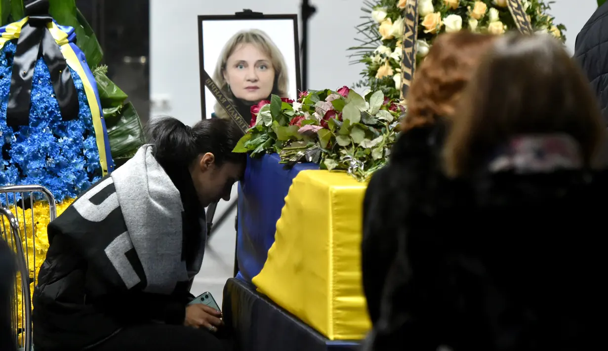 Keluarga duduk disamping peti jenazah korban yang tewas dalam insiden jatuhnya pesawat Ukraine International Airlines di Iran (8/1) lalu, Bandara Boryspil Kiev, Ukraina, Minggu (19/1/2020). Pesawat tersebut jatuh oleh rudal pasukan IRGC. (Ukrainian Presidential Press Service/AFP)
