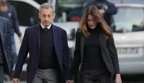 Mantan Presiden Prancis Nicolas Sarkozy dan istrinya, Carla Bruni-Sarkozy, meninggalkan rumah mereka di Paris pada Selasa (21/10/2025). Sarkozy menuju penjara untuk menjalani hukuman atas kasus pendanaan ilegal kampanye pemilihannya tahun 2007, yang diduga berasal dari Libya. (Dok. AP/Thibault Camus)&nbsp;&nbsp;&nbsp;