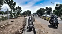 Pengendara motor melintasi pekerja yang beraktivitas saat menerobos flyover tapal kuda Lenteng Agung, Jakarta, Minggu (28/2/2021). Peristiwa ini dapat membahayakan pengendara sepeda motor karena aktivitas pembangunan flyover masih berlangsung. (merdeka.com/Iqbal S Nugroho)