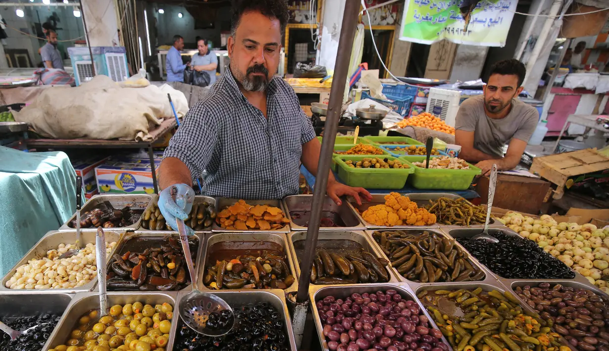 Seorang pedagang menjual zaitun dan acar sayuran di pasar populer di Baghdad, Irak (24/5/2019). Umat Muslim di seluruh dunia tengah melaksanakan puasa dimana mereka tidak makan, minum mulai dari matahari terbit hingga terbenam. (AFP Photo/Ahmad Al-Rubaye)