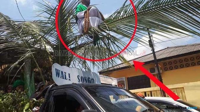 Orang Sakti yang meniru dandanan wali songo itu duduk di atas pelepah kelapa yang diarak dengan mobil pick up. (prokal/Jawapos)