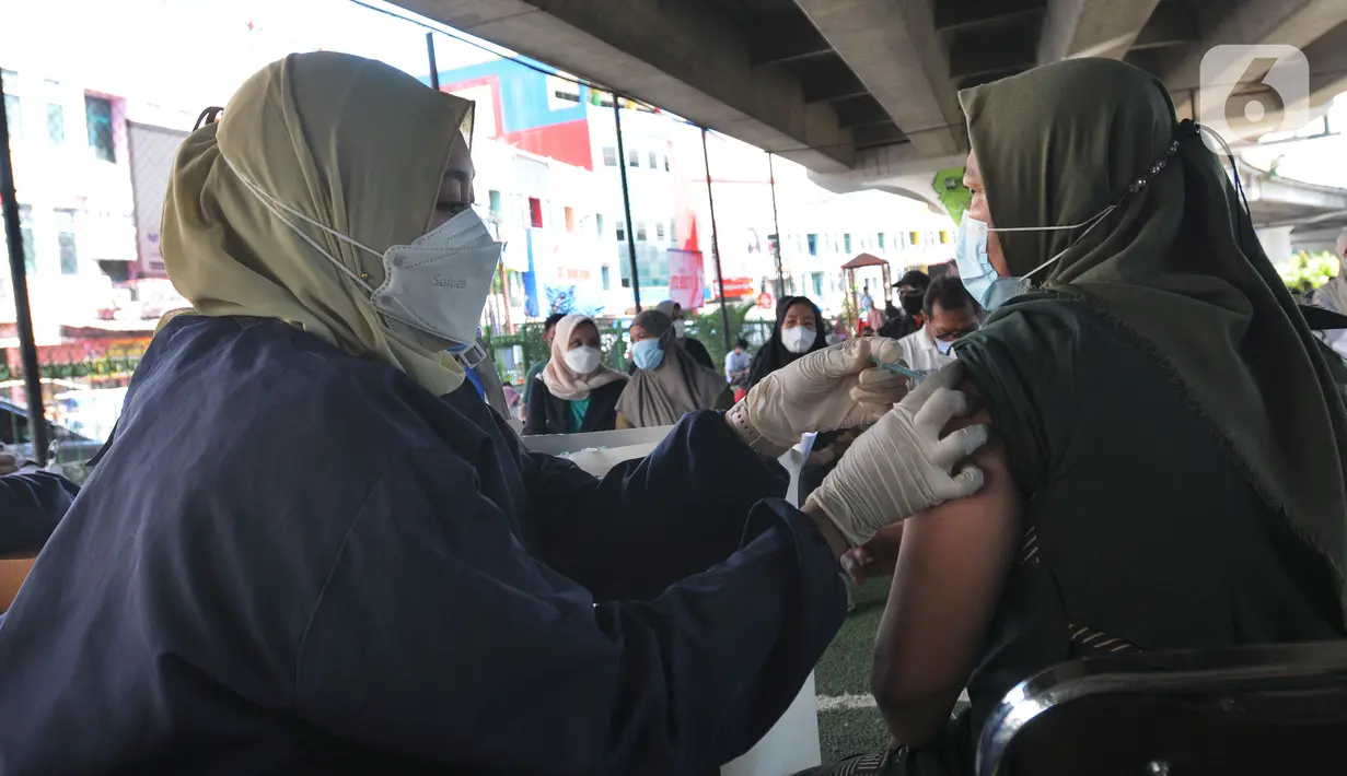 Petugas kesehatan menyuntikkan vaksin dosis ketiga kepada seorang perempuan di kolong flyover Ciputat, Tangerang Selatan, Sabtu (2/4/2022). Selain untuk melengkapi vaksin COVID-19, booster menjadi syarat perjalanan mudik lebaran tahun 2022. (merdeka.com/Arie Basuki)