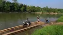 Warga bersama sepeda motornya menyeberangi Sungai Cisadane menggunakan rakit bambu di kawasan Ciseeng, Kabupaten Bogor, Jawa Barat, Kamis (11/6/2026). (merdeka.com/Arie Basuki)