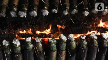 Pekerja membakar lemang atau beras ketan yang dimasukan ke bambu di kawasan Senen, Jakarta, Rabu (29/3/2023). (Liputan6.com/Herman Zakharia)