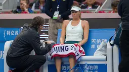 Maria Sharapova berbincang dengan pelatih saat istirahat selama pertandingan melawan Simona Halep dari Rumania pada  turnamen tenis China Terbuka di Diamond Court, Beijing (4/10). Sharapova kalah 6-2 6-2 dalam waktu 72 menit. (AFP Photo/Nicolas Asfouri)