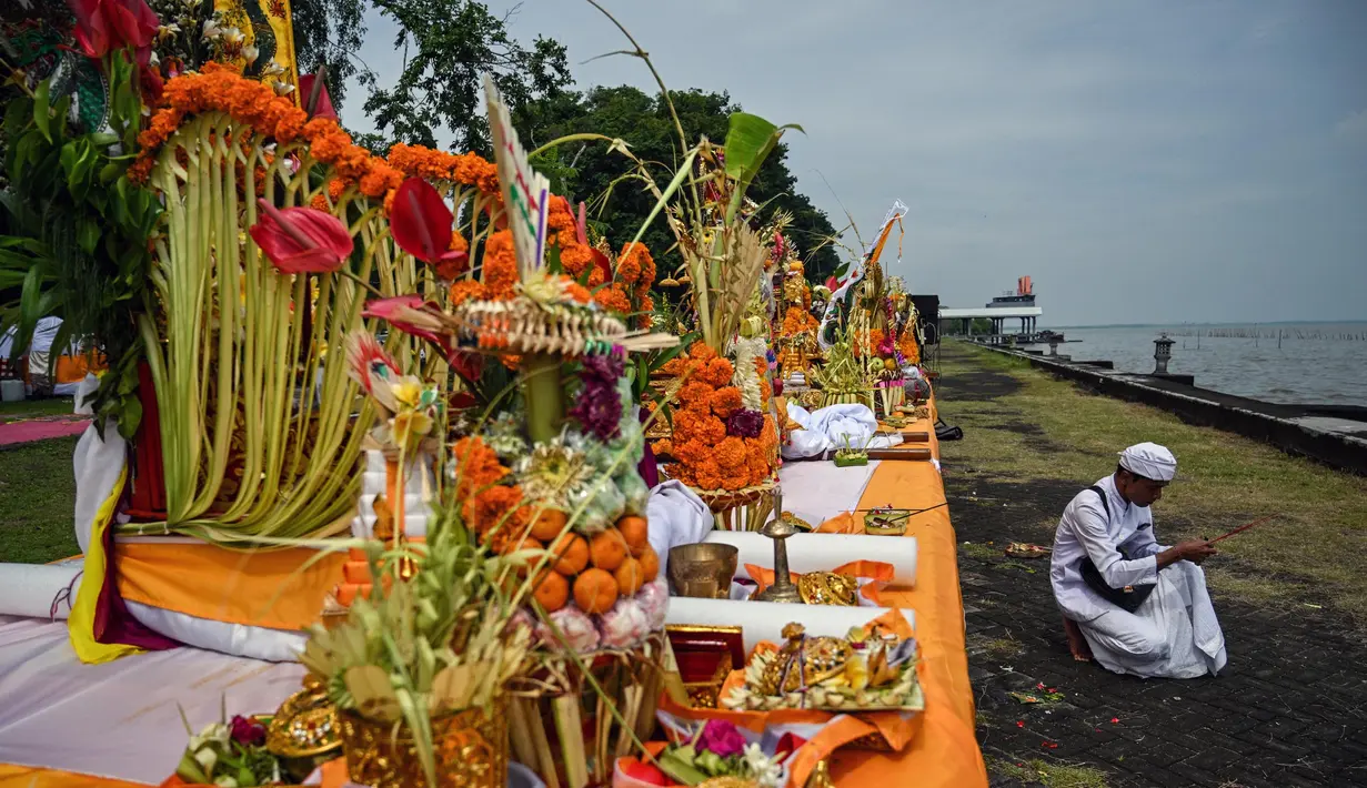 Seorang umat Hindu mempersiapkan persembahan untuk sembahyang selama upacara ritual Melasti di Pantai Arafuru, Surabaya, 23 Maret 2025. (JUNI KRISWANTO/AFP)