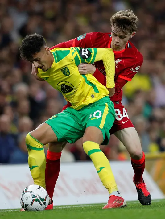 Bek Liverpool Conor Bradley (kanan) bersaing dengan bek Norwich City Dimitris Giannoulis pada babak ketiga Piala Liga Inggris di Carrow Road, Rabu (22/9/2021) dinihari WIB. Liverpool sukses menghajar Norwich City tiga gol tanpa balas di kandang lawan. (ADRIAN DENNIS / AFP)